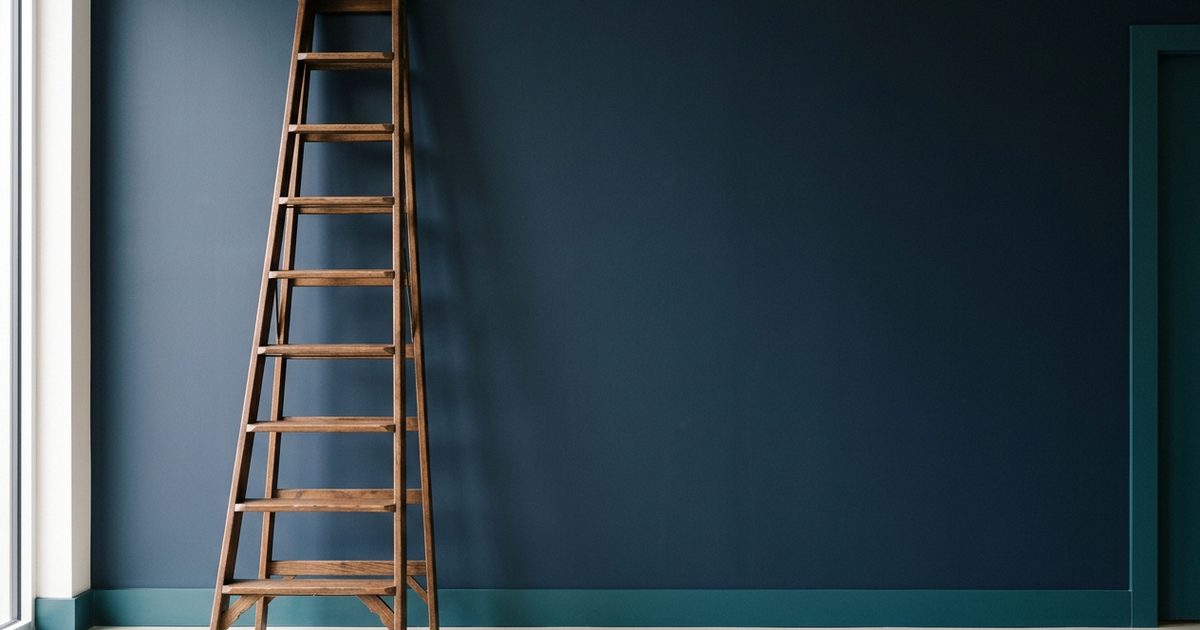 Hohe Holzleiter, die an einer dunkelblauen Wand lehnt