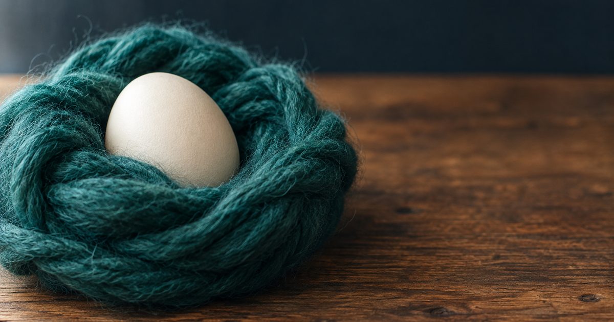 Ein Ei in einem weichen Nest aus türkiser Wolle